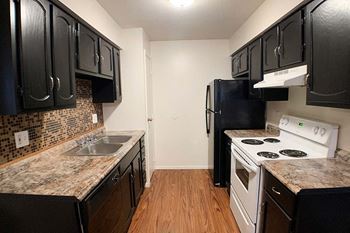 a kitchen with black cabinets and white appliances at Hunter Ridge Apartments, Cincinnati, Ohio