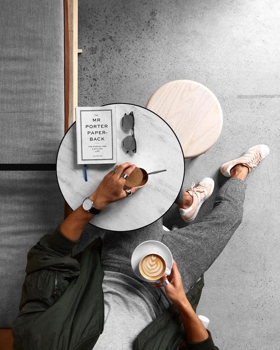 a person sitting at a table with a cup of coffee and a book
