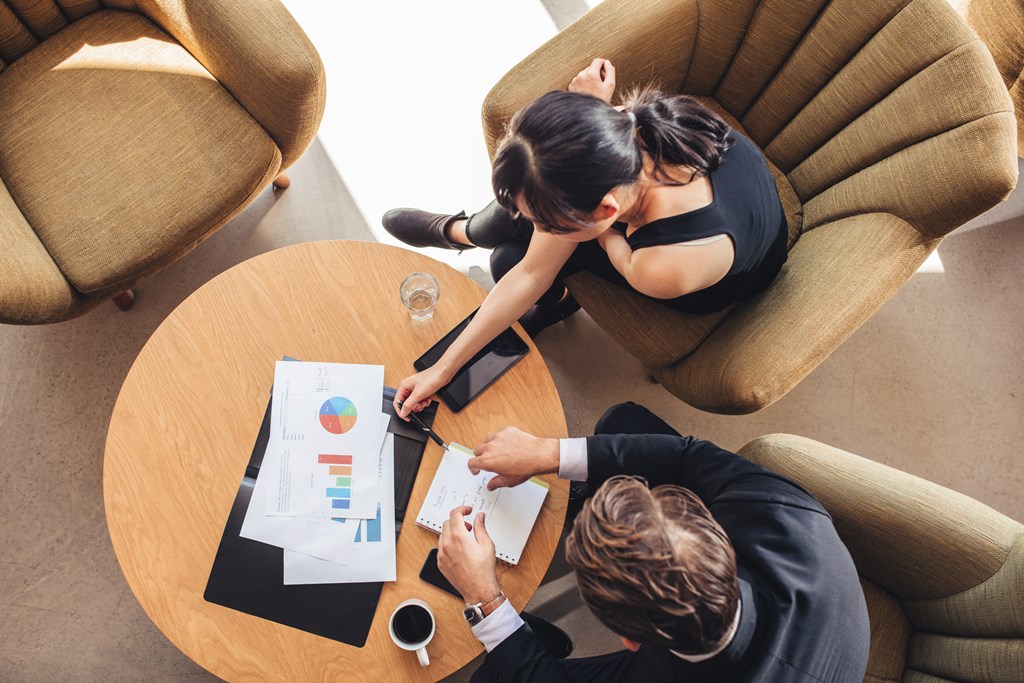 a man and woman sitting at a table looking at a piece of paper