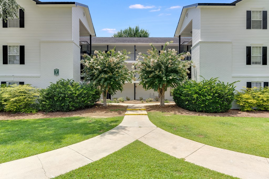 a walkway leading to an apartment building with white siding and a gray roof at Dothan Farms, Alabama, 36305