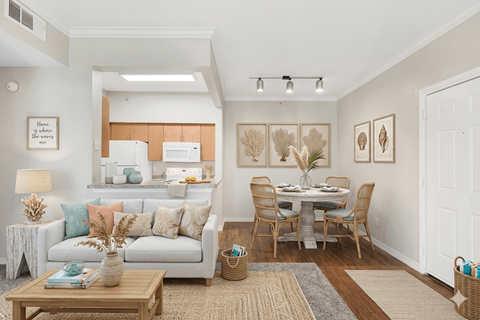 A well-lit, modern living room with a dining area and a kitchen in the background.