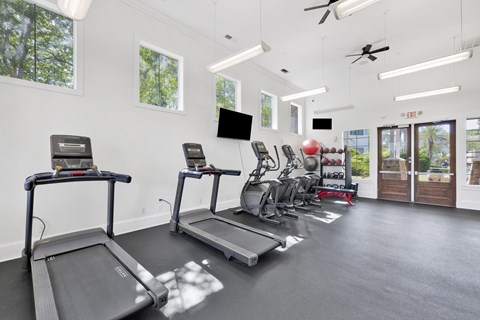 A gym with treadmills, exercise bikes, and a television.