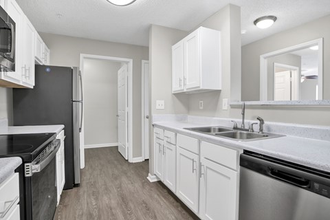 A kitchen with white cabinets and a black refrigerator.
