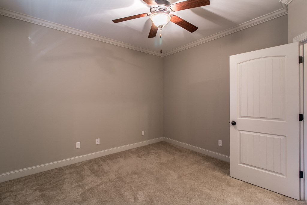 an empty bedroom with a ceiling fan and a white door