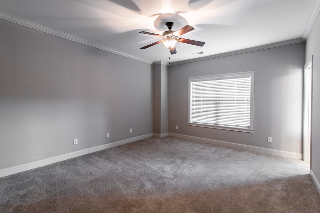an empty living room with a ceiling fan and a window