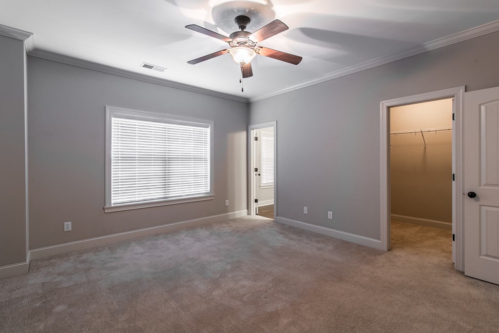 an empty living room with a ceiling fan and a closet