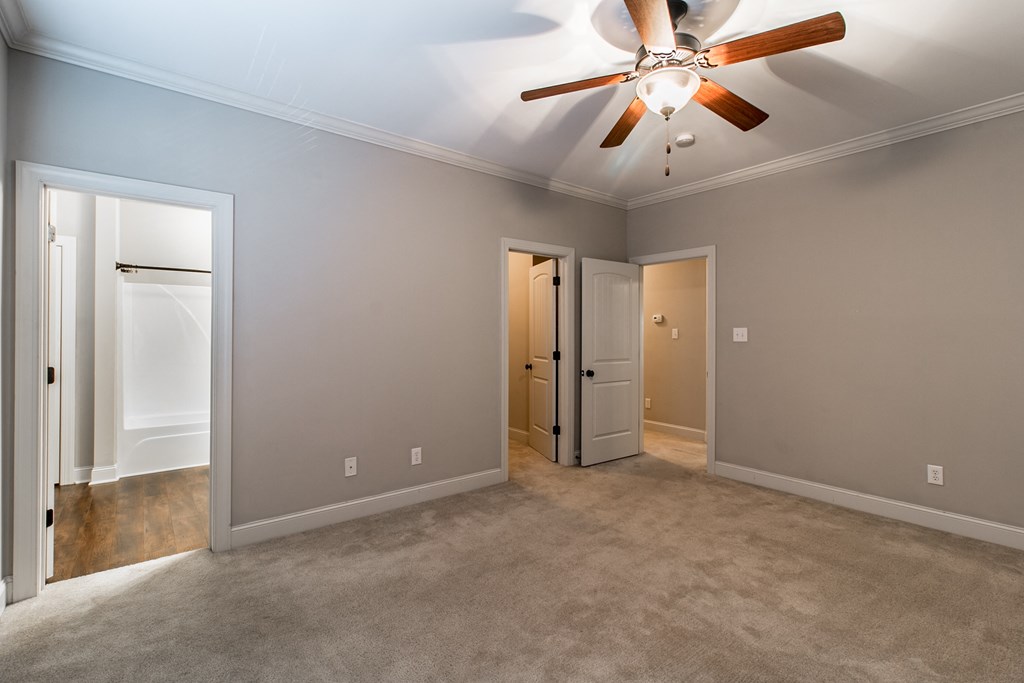 an empty living room with a ceiling fan and a door to a closet