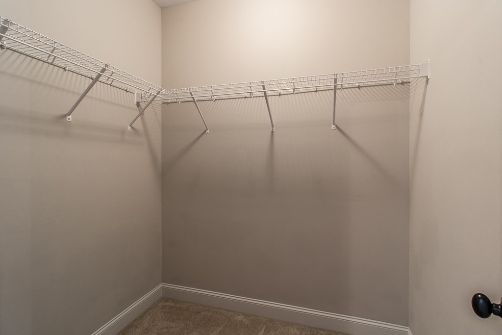 a walk in closet in a bedroom with a hanging rack on the wall