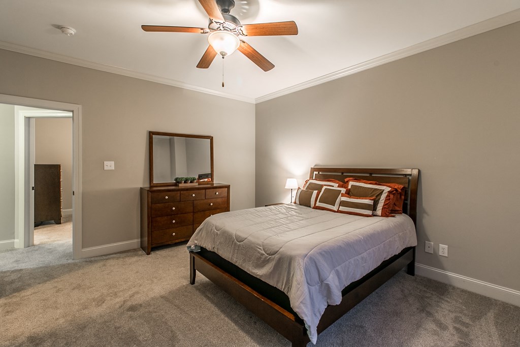 the master bedroom has a king sized bed and a ceiling fan