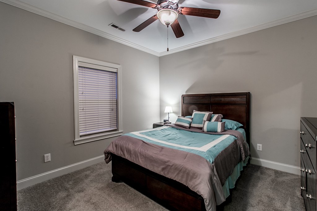 the master bedroom has a king sized bed and a ceiling fan