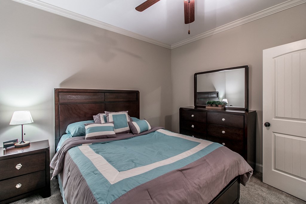 a bedroom with a bed and two dressers and a ceiling fan