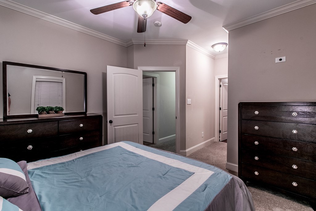 a bedroom with a bed and dressers and a ceiling fan