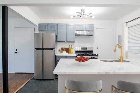 a kitchen with a marble counter top and stainless steel refrigerator