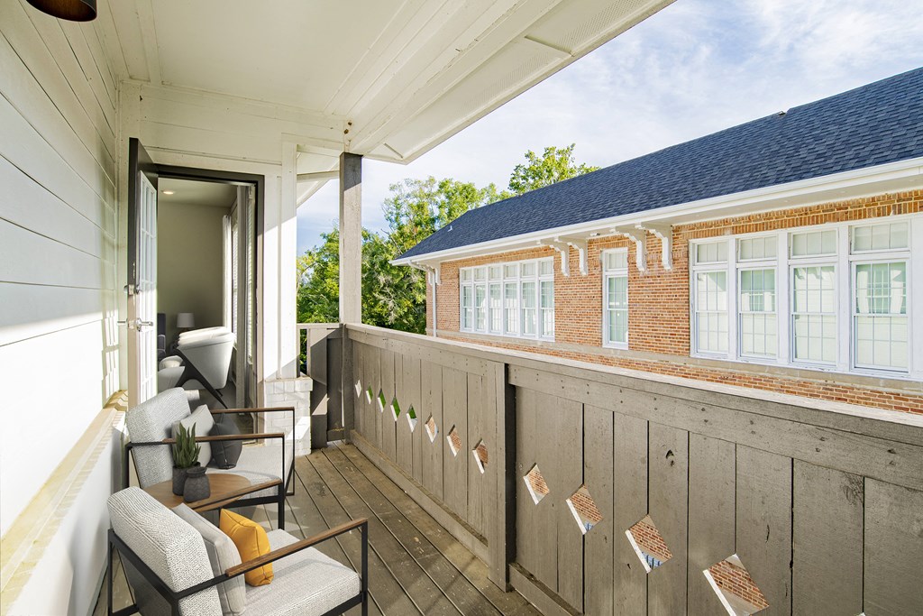 a balcony with a couch and chairs and a brick building