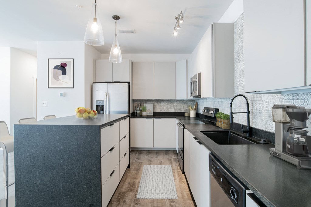 a modern kitchen with black counter tops and white cabinets
