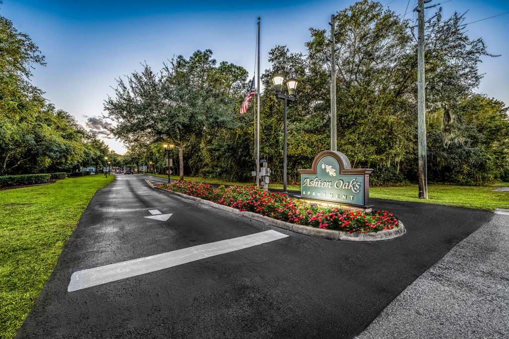 the welcome sign at the end of a road with flowers