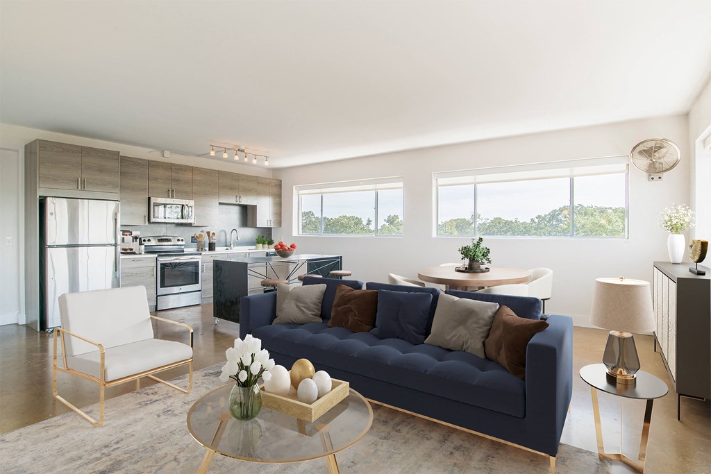 a living room with a blue couch and a kitchen in the background