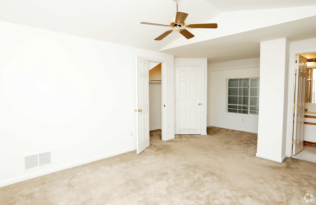 an empty living room with a ceiling fan and a closet
