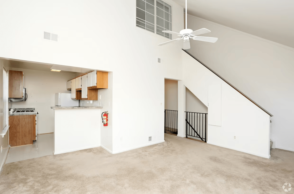 an empty living room with white walls and a ceiling fan