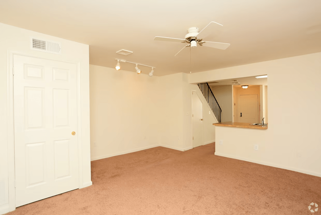 an empty living room with a ceiling fan