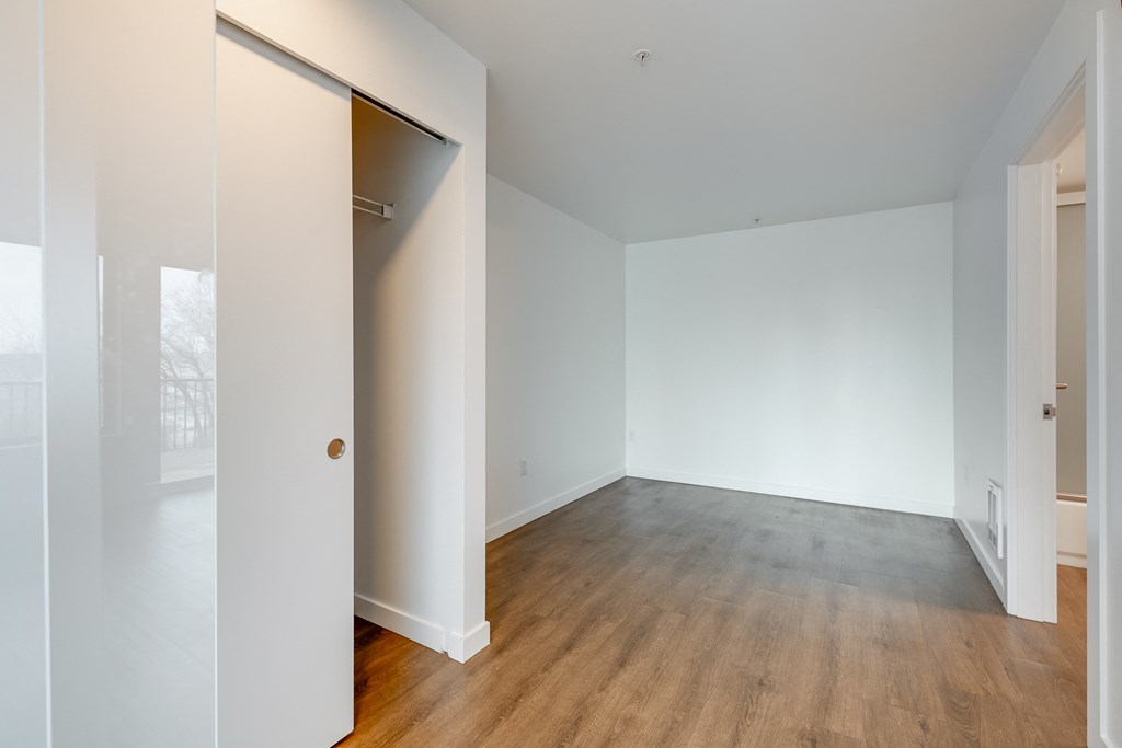 an empty living room with white walls and a wood floor