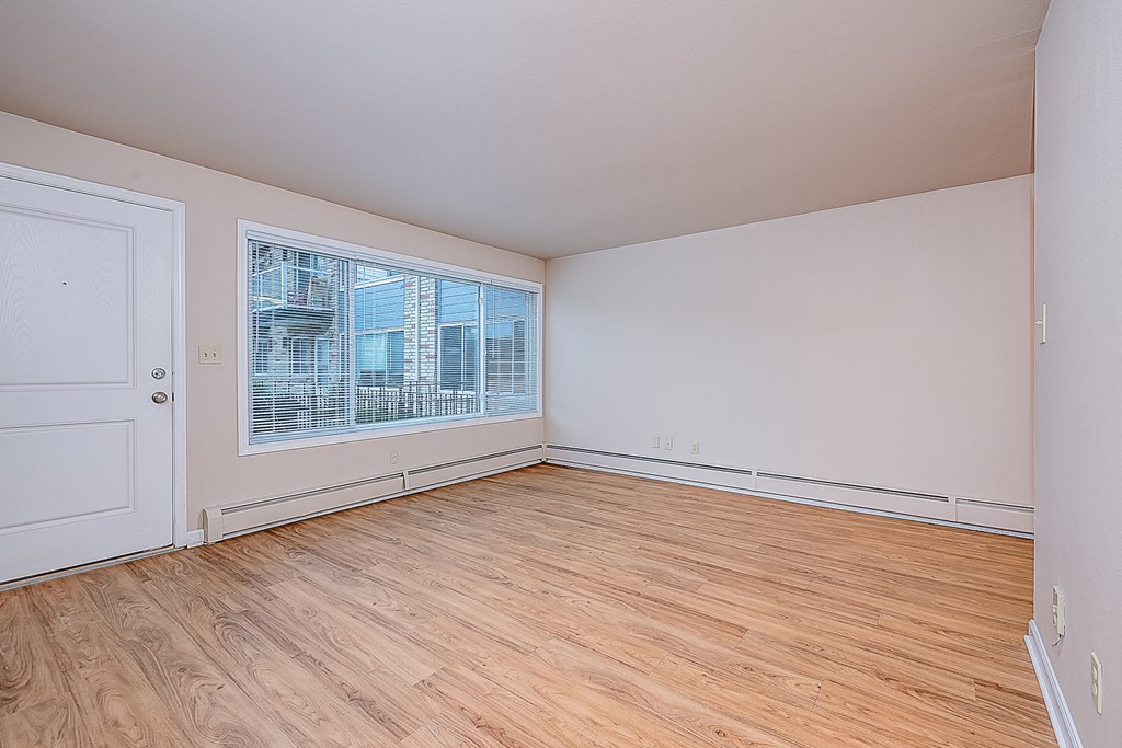 an empty living room with wood floors and a large window