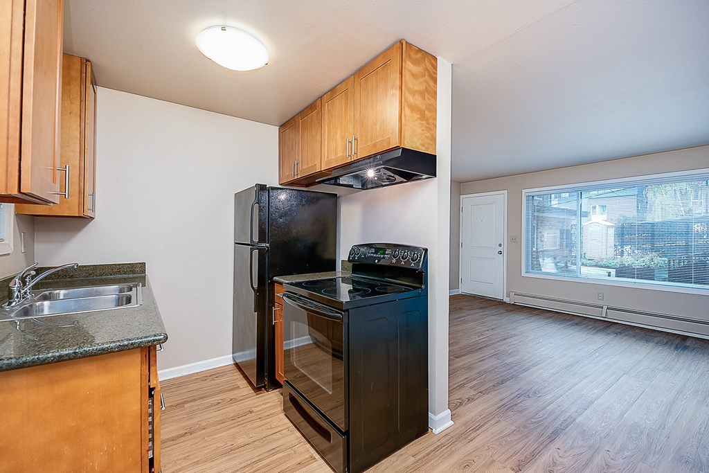 an empty kitchen with black appliances and wood floors