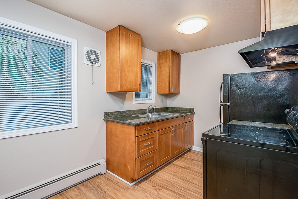 a kitchen with black appliances and wooden cabinets and a window