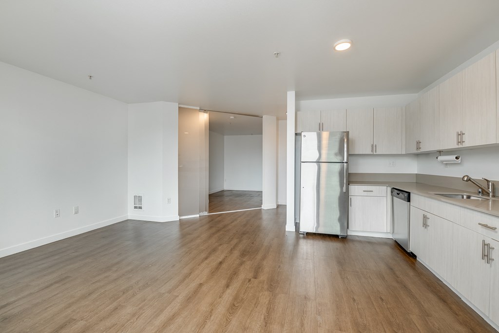 an empty kitchen with white cabinets and a stainless steel refrigerator