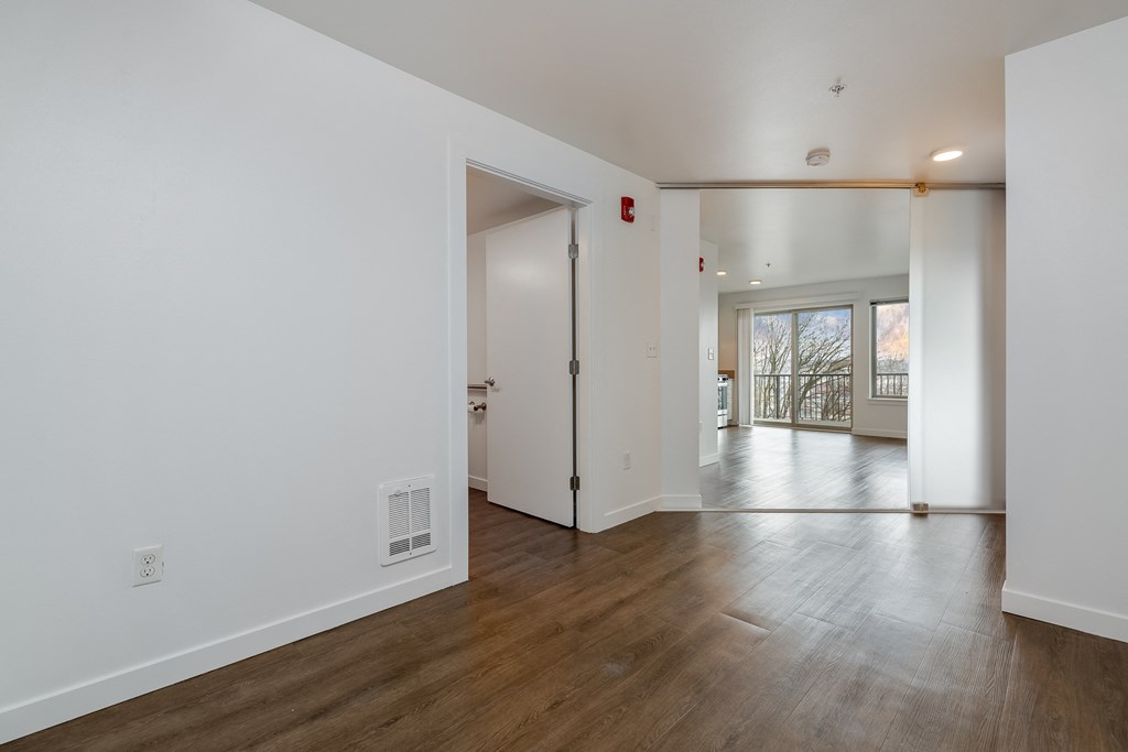 a living room and dining room with white walls and wood floors