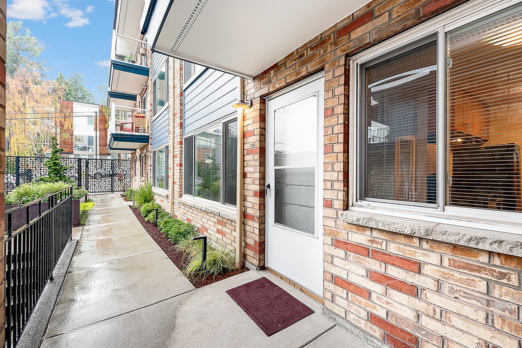 the front door of a brick apartment building with a sidewalk
