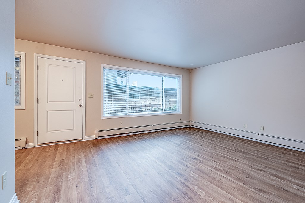 an empty living room with wood flooring and a window