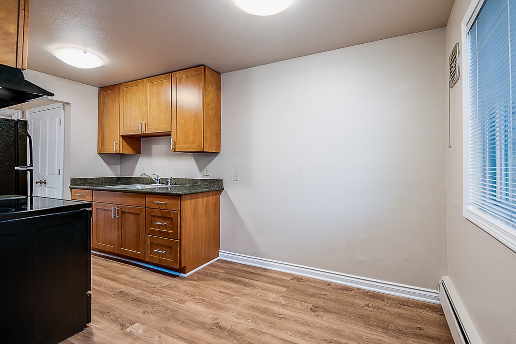 an empty kitchen with wooden cabinets and a window