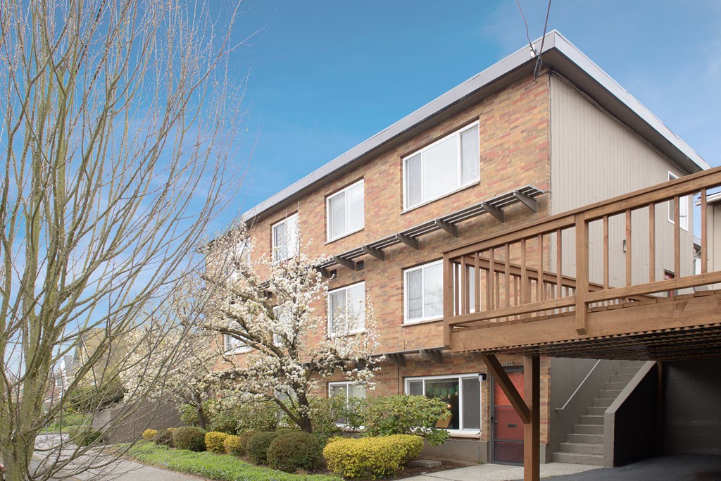 the exterior of a home with a wooden deck and a tree in front of it