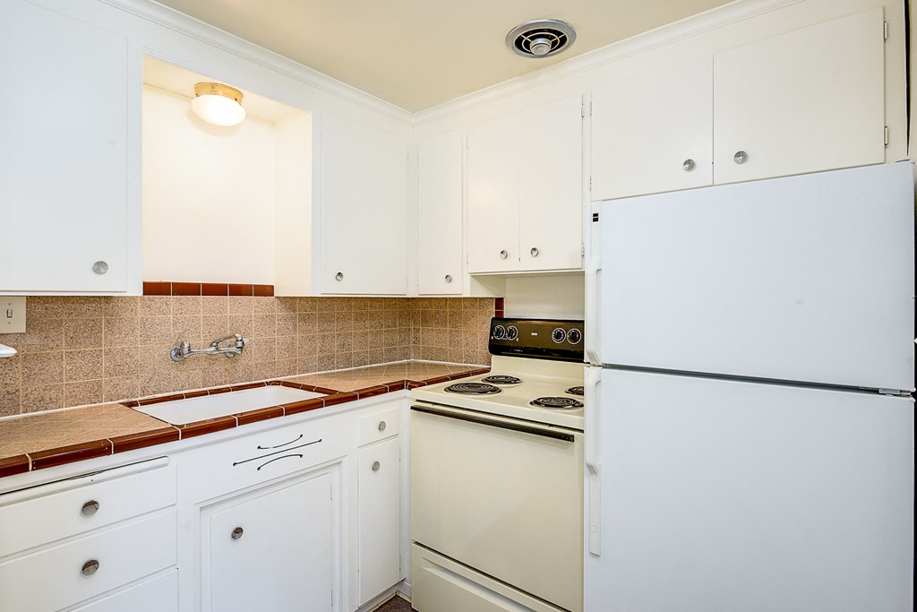 a kitchen with white cabinets and a stove and refrigerator