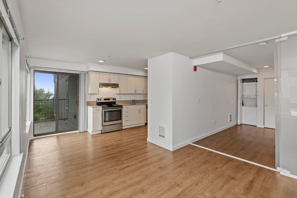 an empty living room and kitchen with a door to a balcony