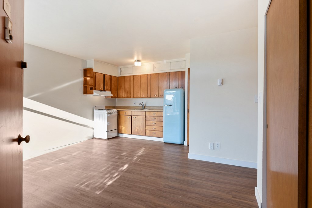 an empty kitchen with wood flooring and a blue refrigerator