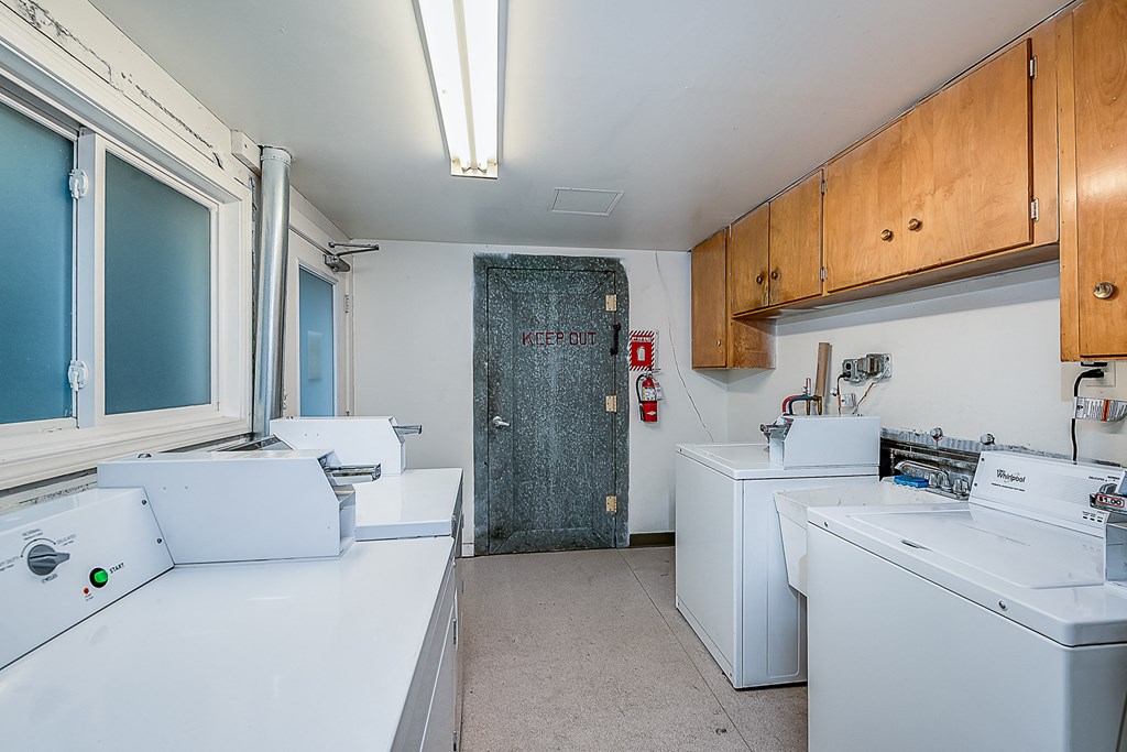 a laundry room with four washer and dryers and a door to a closet