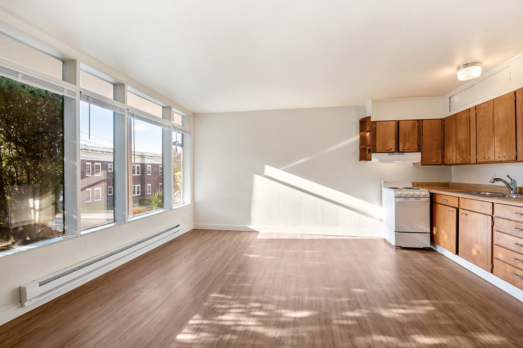 an empty living room with a large window and a kitchen