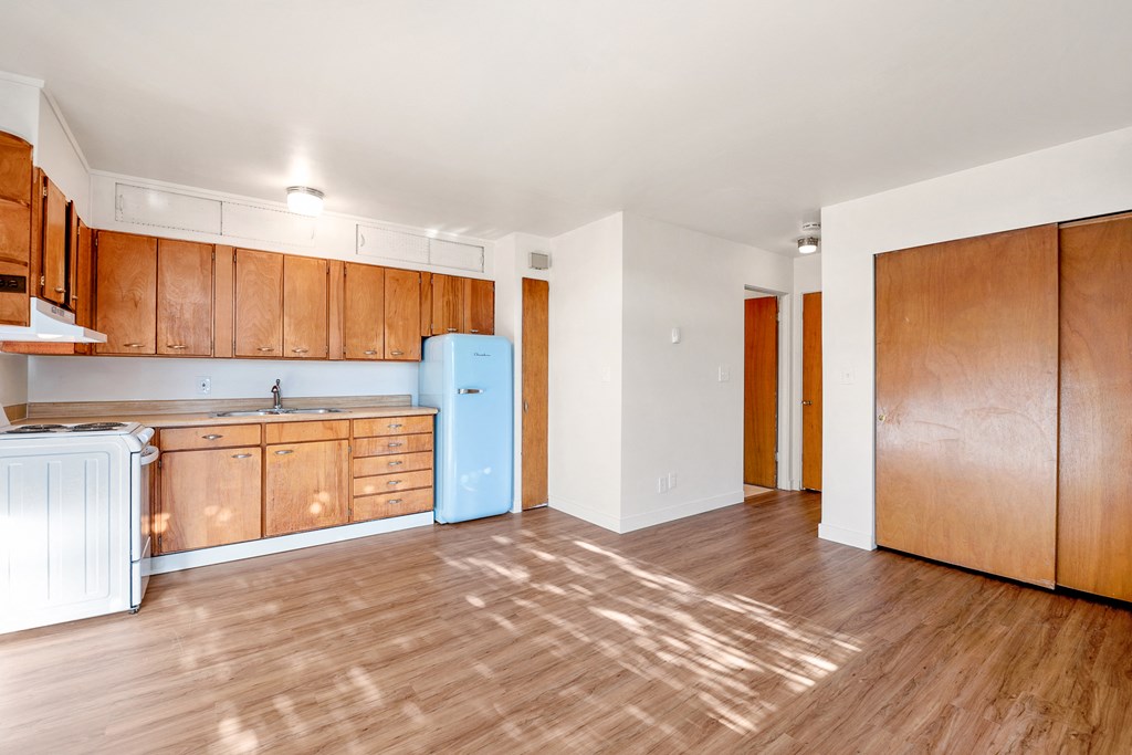 an empty kitchen with wooden cabinets and a blue refrigerator