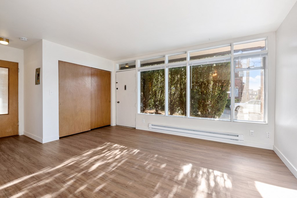 an empty living room with a large window and wooden floors