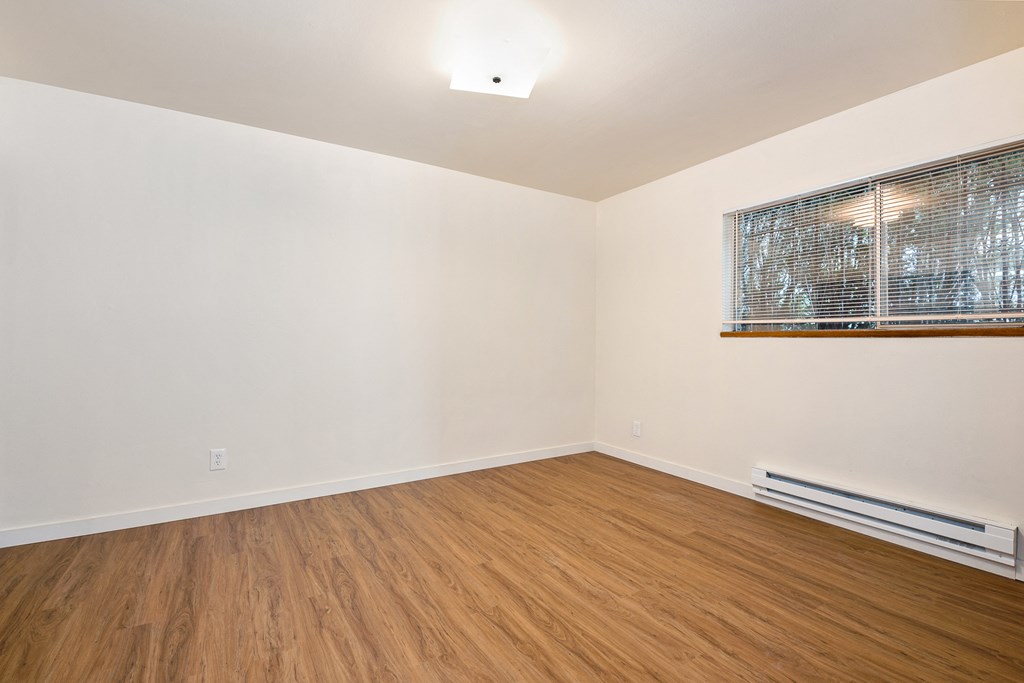 an empty living room with wood flooring and a window