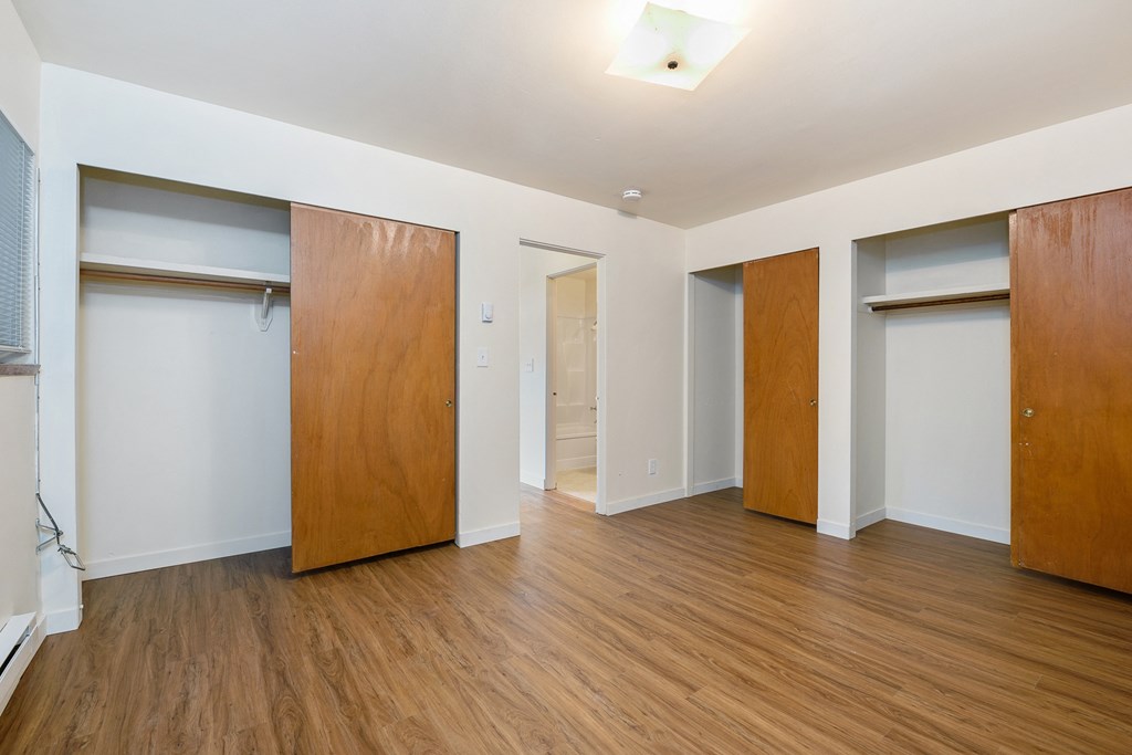 a living room with wood flooring and white walls and wooden doors