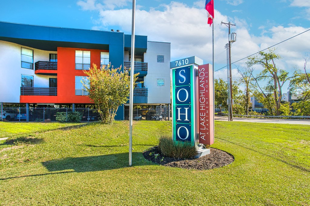 a sign in front of a motel with a building in the background