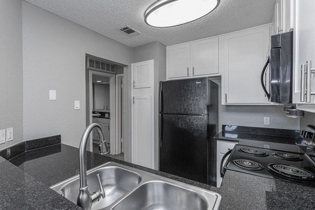 A kitchen with a black fridge and stove top oven.
