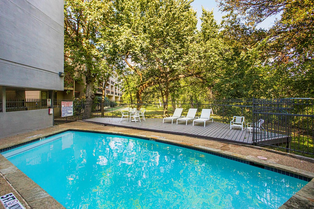 a swimming pool with chairs and a building in the background