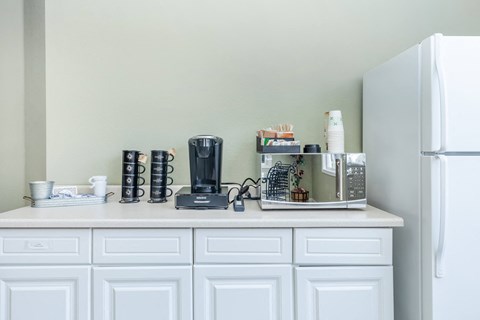 a kitchen counter with a coffee machine and a refrigerator