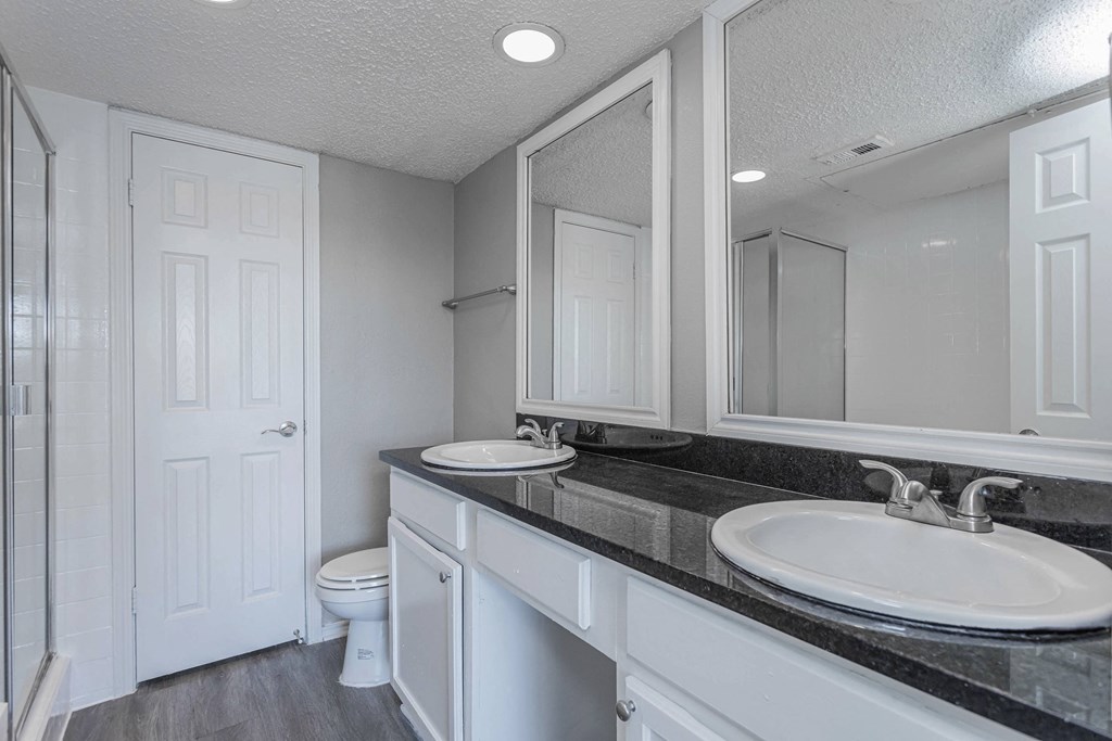 A bathroom with a sink, toilet, and mirror.
