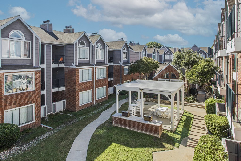 A sunny day at a residential complex with apartment buildings and a central courtyard.