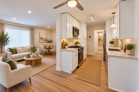 Staged Ocean View Townhomes modern kitchen with white cabinets and a wooden floor.
